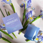 GP Candle Co Midnight 9oz Candle box and candle lying with purple irises