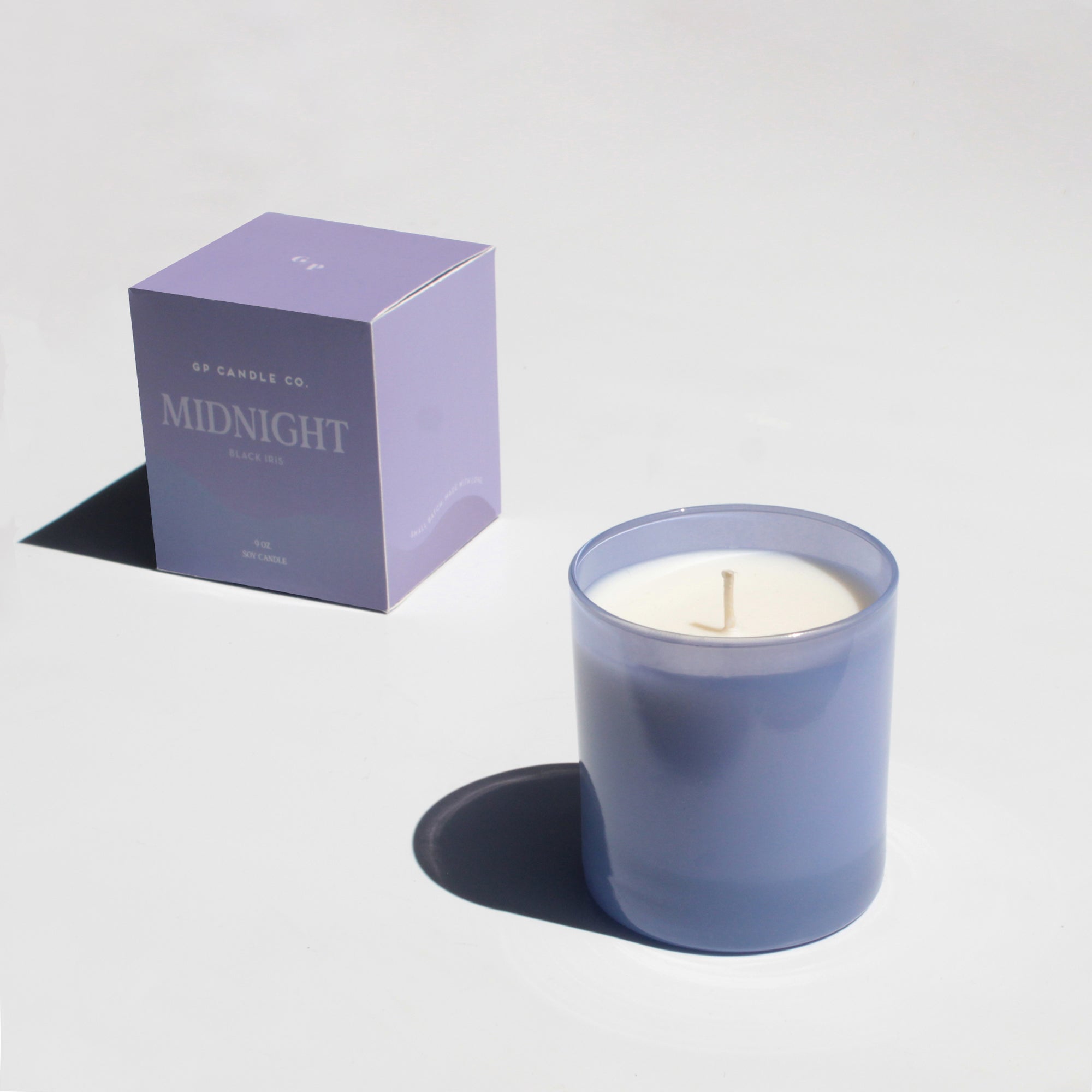 GP Candle Co Midnight 9oz Candle in a blue glass jar beside its purple box on white
