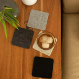 Graf Lantz Bierfilzl Square Coasters in Noir on a wooden table with an iced drink and greenery