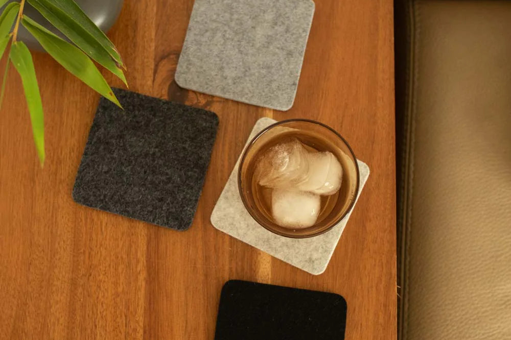 Graf Lantz Bierfilzl Square Coasters in Noir on a wooden table with an iced drink and greenery