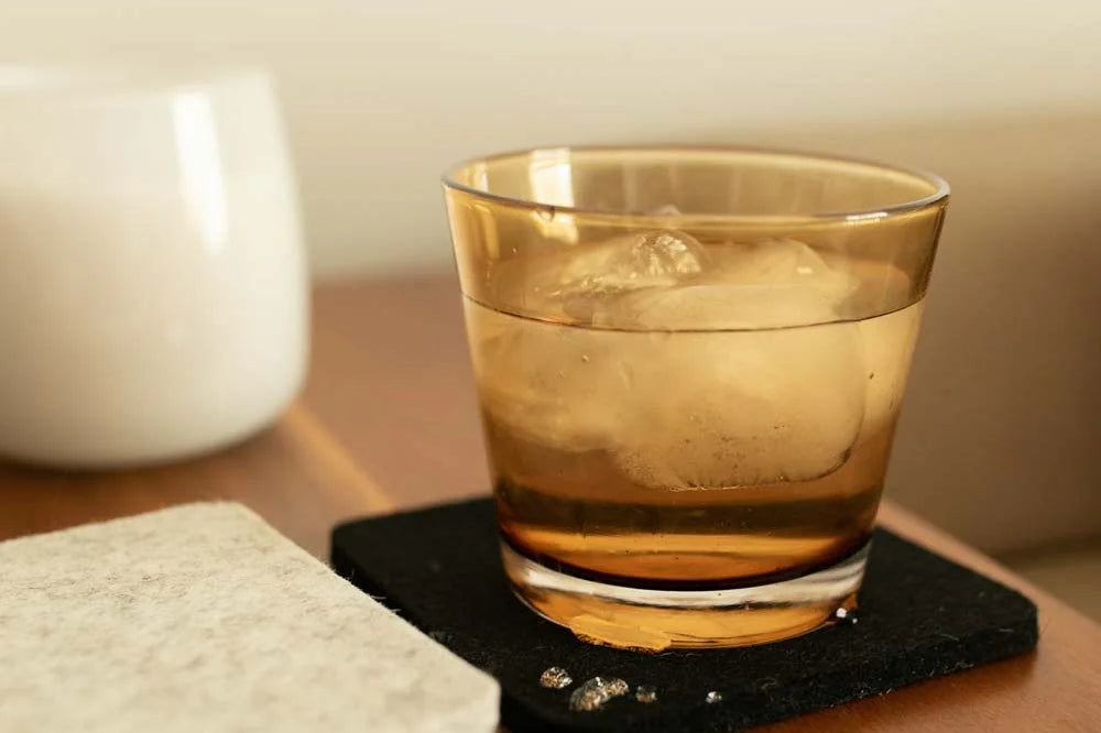 Graf Lantz Bierfilzl Square Coaster in black under a glass of whiskey on a side table