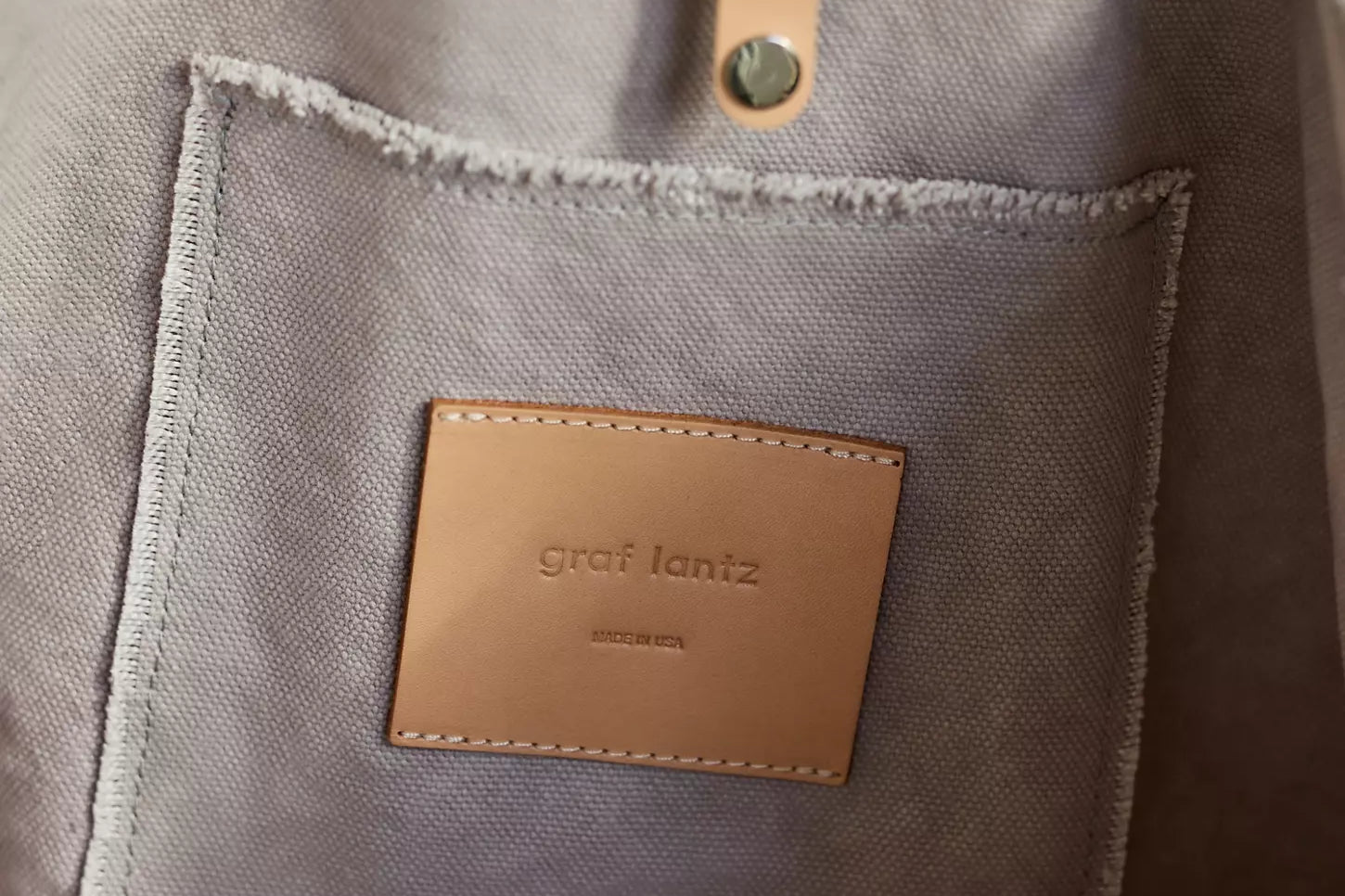 Close-up of the leather Graf Lantz label and rivet on the Hana Canvas Boat Bag in gray