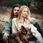 Couple sitting outdoors with a German shepherd, the woman holding Guy Fox Palmer Men's Cologne