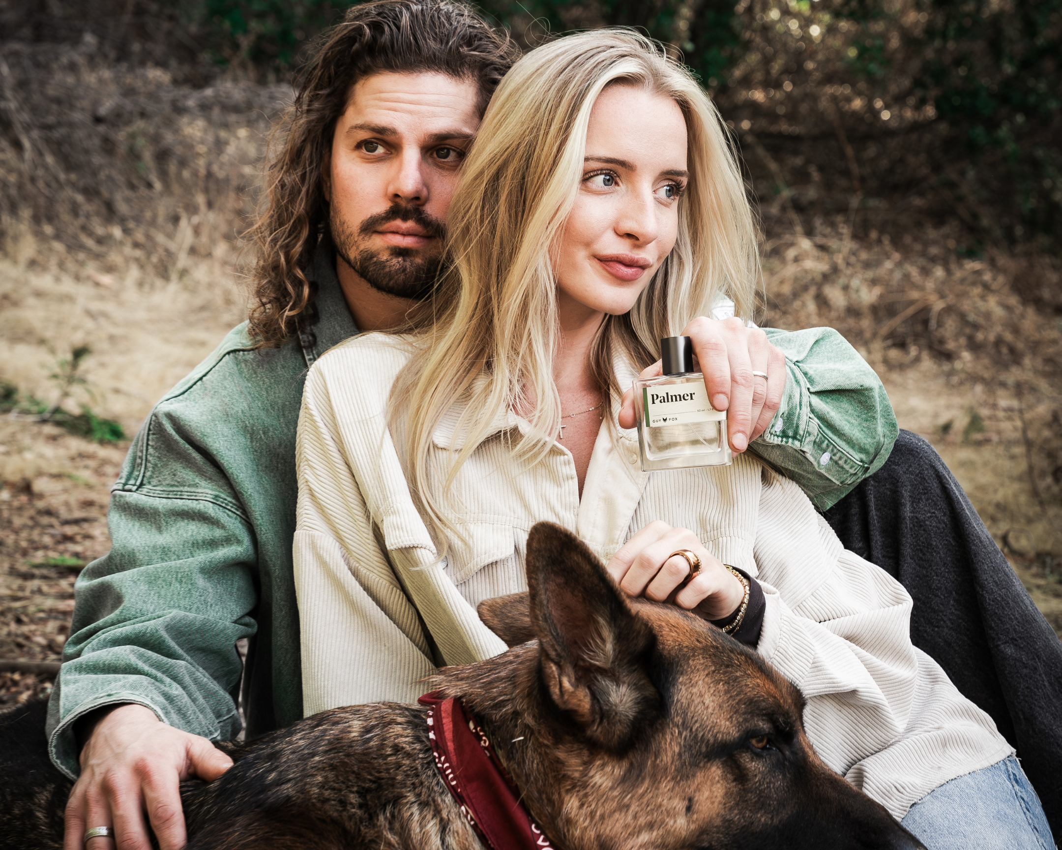Couple sitting outdoors with a German shepherd, the woman holding Guy Fox Palmer Men's Cologne