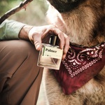 Man holding Guy Fox Palmer Men's Cologne beside a German shepherd in a red bandana
