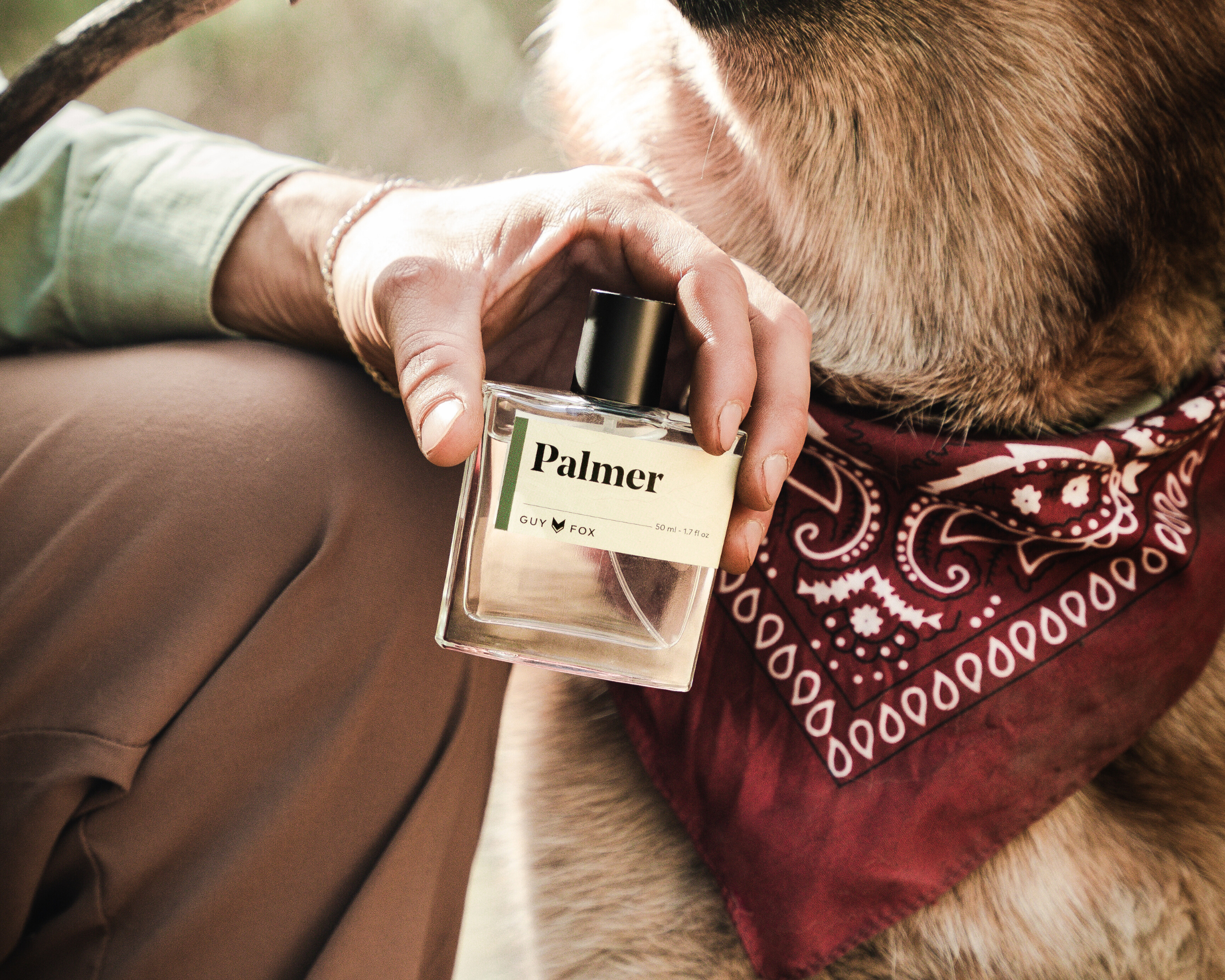 Man holding Guy Fox Palmer Men's Cologne beside a German shepherd in a red bandana