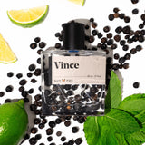 Guy Fox Vince Cologne bottle lying among black peppercorns, mint leaves and lime slices