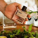 Hand holding the Guy Fox Vince Cologne bottle over a tray of mint and drinks