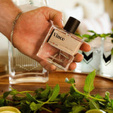 Hand holding the Guy Fox Vince Cologne bottle over a tray of mint and drinks