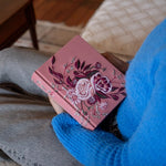 Person in a blue sweater holding the Hosanna Revival CSB Notetaking Bible Rosedal theme in their lap