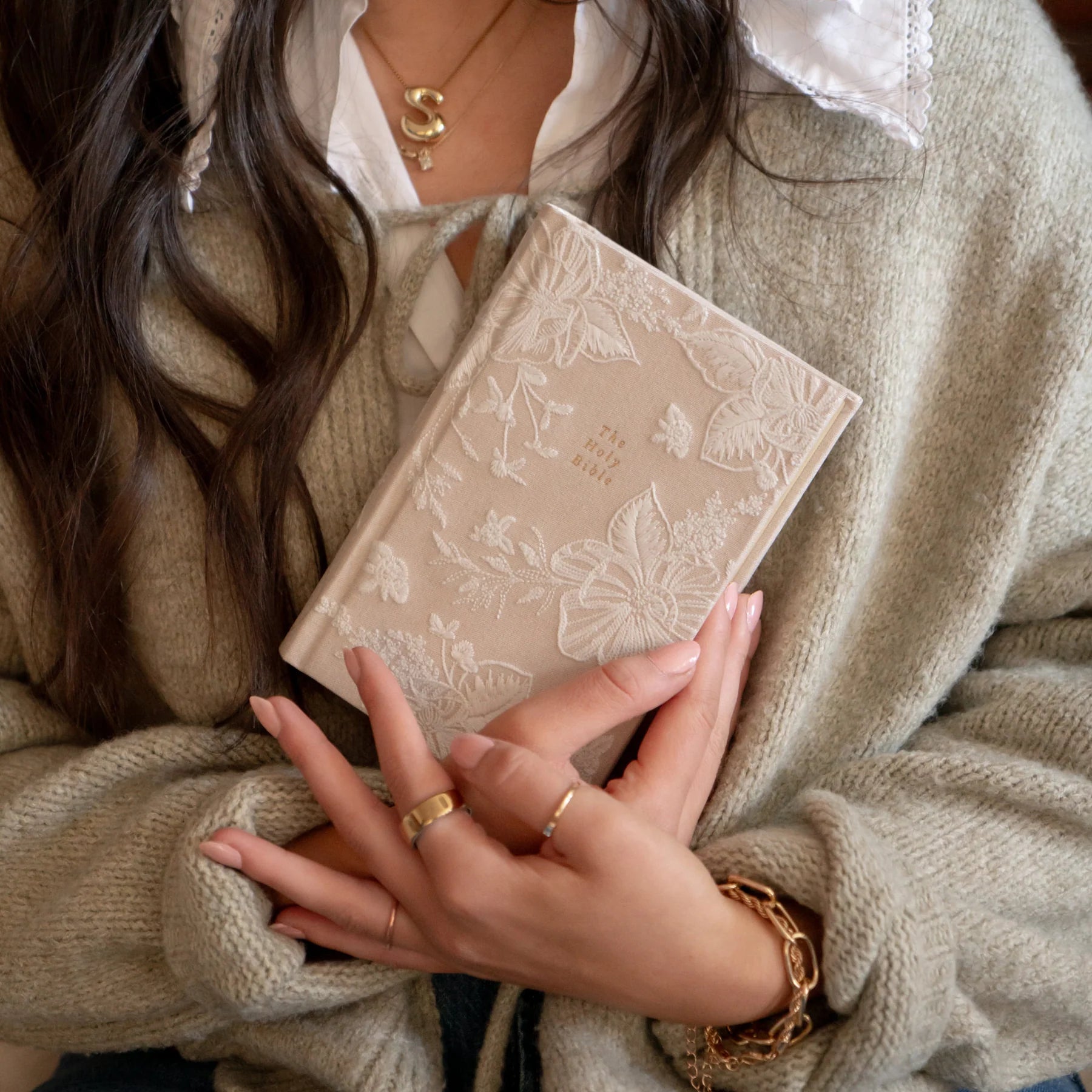 Woman in a beige sweater holding the Hosanna Revival NLT Compact Bible in the Casablanca theme
