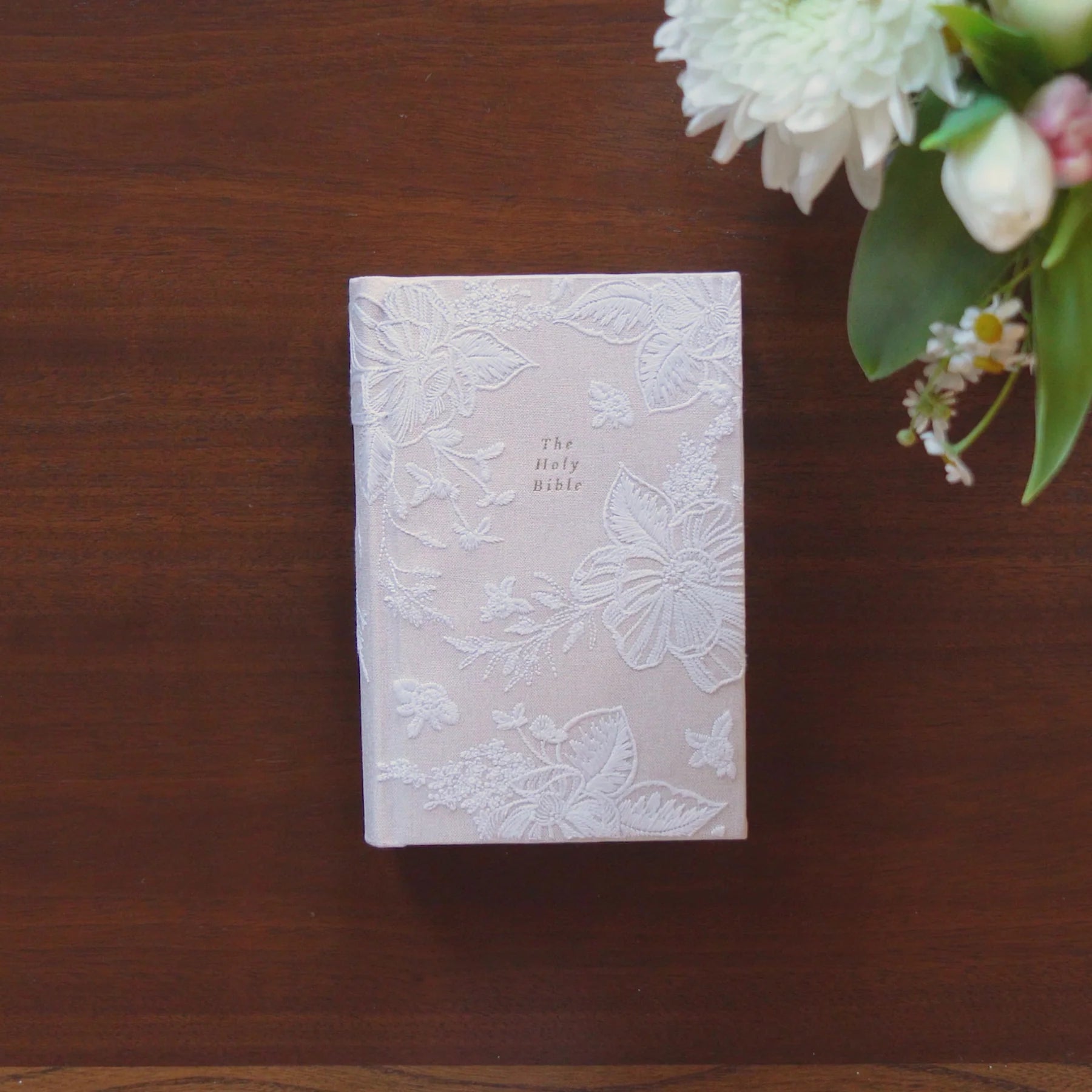 Hosanna Revival NLT Compact Bible Casablanca theme on a dark wood table with white flowers