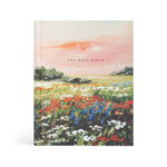 Hosanna Revival NLT Notetaking Bible in the Coram theme, a painted wildflower meadow under a pink sky