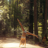 Woman doing a cartwheel on a sunlit forest path wearing the Huha Mineral Bikini underwear in Grey