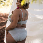 Woman glancing over her shoulder outdoors wearing the Huha Mineral Bikini underwear and bralette in Grey