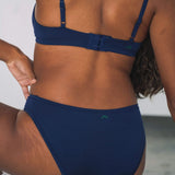 Close-up back view of a woman wearing the Huha Mineral Bikini underwear and bralette in Navy