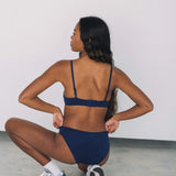 Woman crouching with her back to the camera wearing the Huha Mineral Bikini underwear in Navy