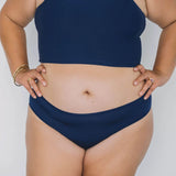 Front view of a woman wearing the Huha Mineral Bikini underwear in Navy with hands on hips