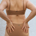 Close-up back view of the Huha Mineral Bikini underwear and bralette in Tan with hands on hips