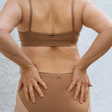 Close-up back view of the Huha Mineral Bikini underwear and bralette in Tan with hands on hips