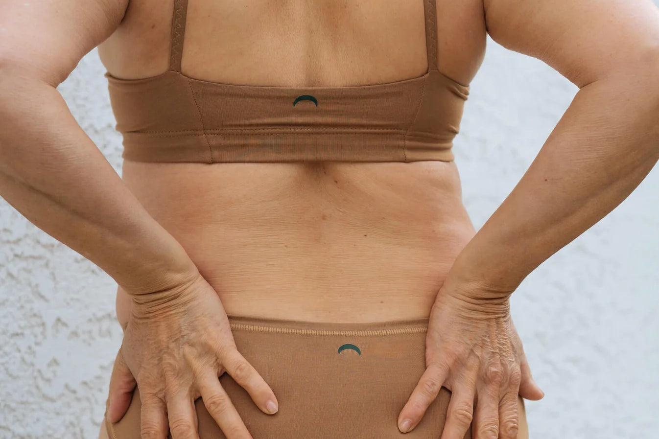 Close-up back view of the Huha Mineral Bikini underwear and bralette in Tan with hands on hips