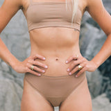 Front view of the Huha Mineral Bikini underwear and bralette in Tan with hands on hips