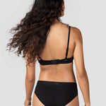 Back view of a woman with long curly hair wearing the Huha Mineral Cheeky underwear and bra in Black