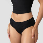 Front view of the Huha Mineral Cheeky underwear in Black worn with a black tank
