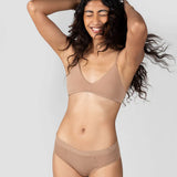 Laughing woman with curly hair wearing the Huha Mineral Cheeky underwear and bralette in Tan