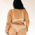 Back view of a woman wearing the Huha Seamless Low Mid Thong and bralette in Beige