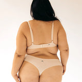 Back view of a woman wearing the Huha Seamless Low Mid Thong and bralette in Beige