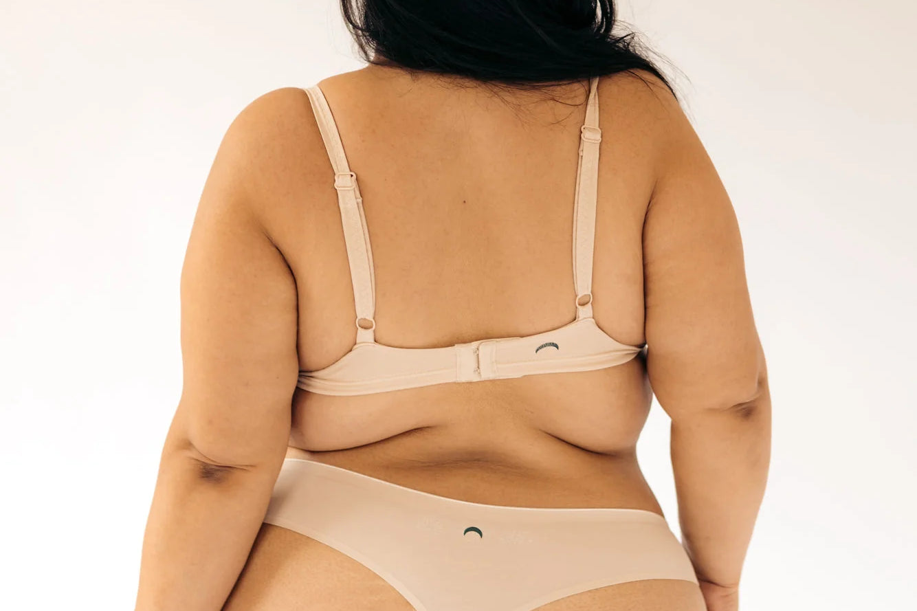 Back view of a woman wearing the Huha Seamless Low Mid Thong and bralette in Beige