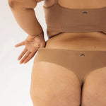 Close-up back view of the Huha Seamless Low Mid Thong and bralette in Tan with hands on hips