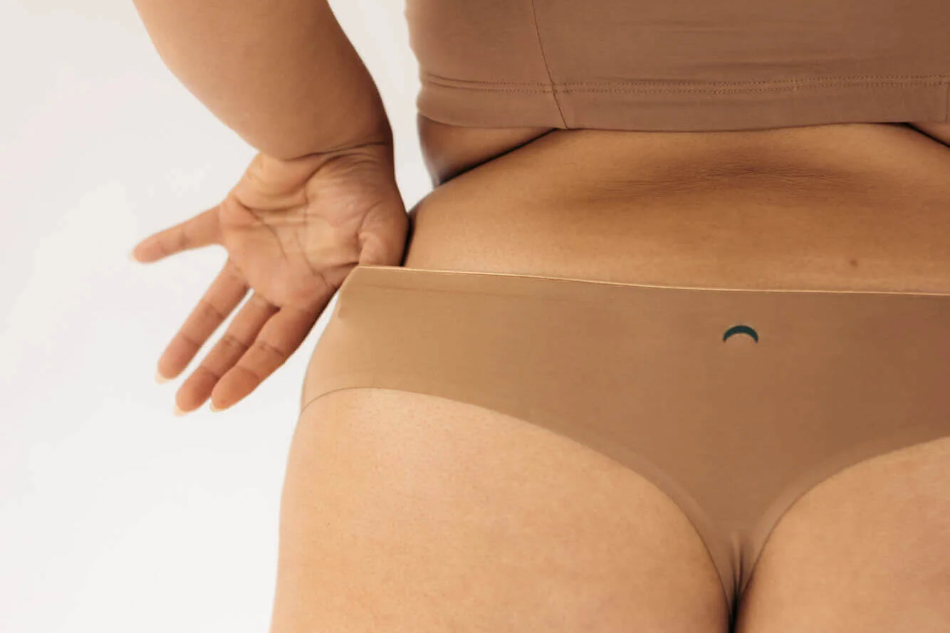 Close-up back view of the Huha Seamless Low Mid Thong and bralette in Tan with hands on hips