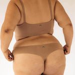 Back view of a woman wearing the Huha Seamless Low Mid Thong and bralette in Tan