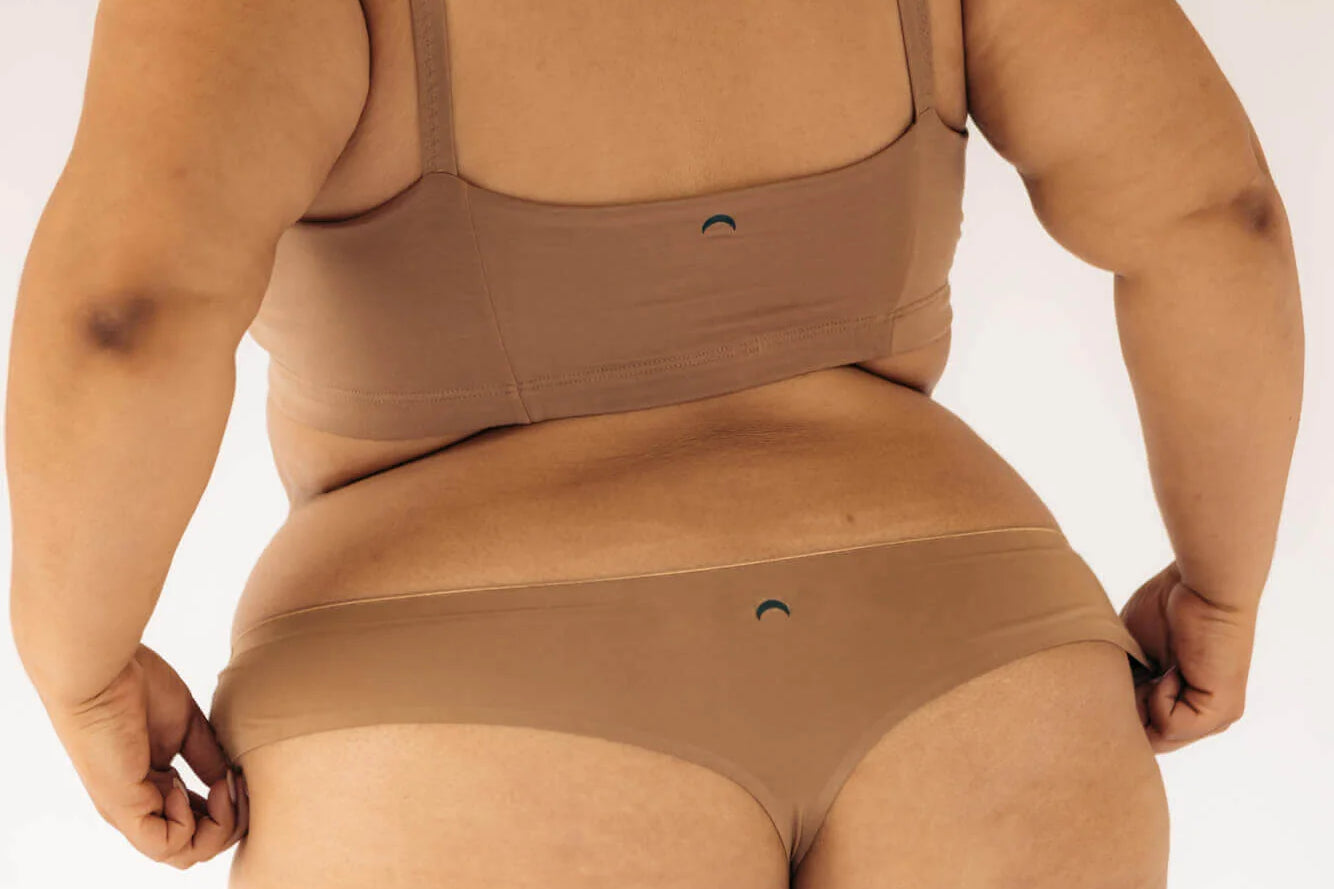 Back view of a woman wearing the Huha Seamless Low Mid Thong and bralette in Tan