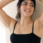 Smiling woman with her arms up wearing the Huha Tata Bralette in Black