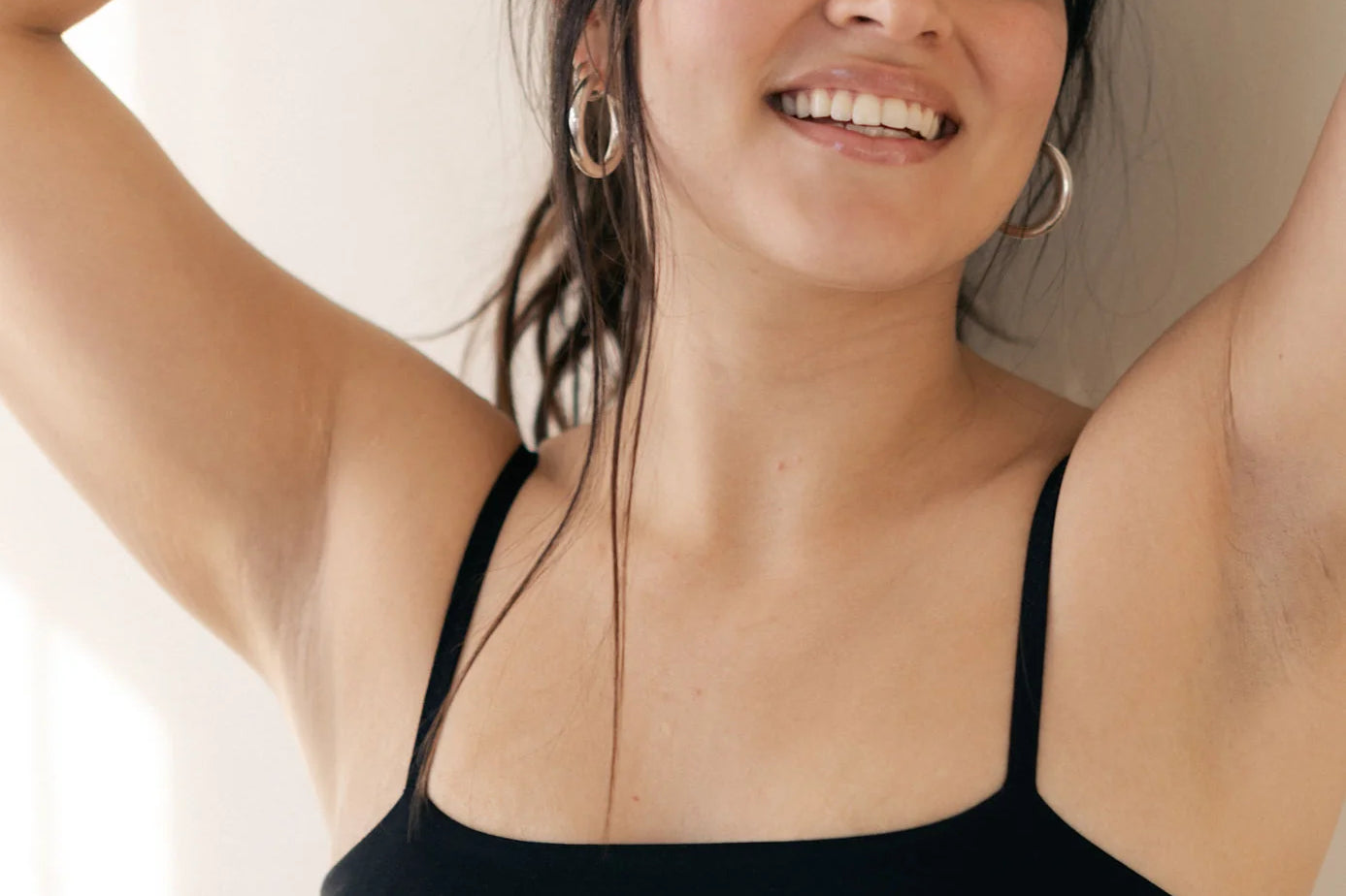 Smiling woman with her arms up wearing the Huha Tata Bralette in Black