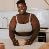 Smiling woman in a kitchen wearing the Huha Tata Bralette and underwear in Grey