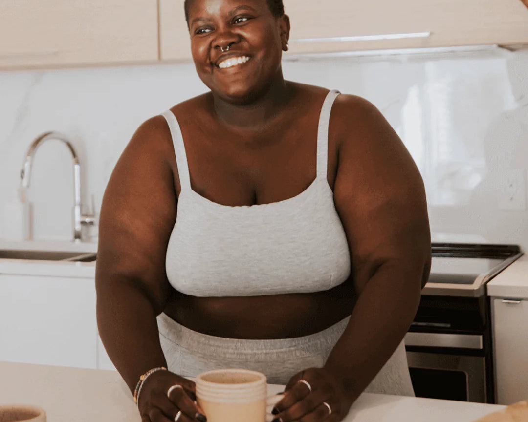 Smiling woman in a kitchen wearing the Huha Tata Bralette and underwear in Grey