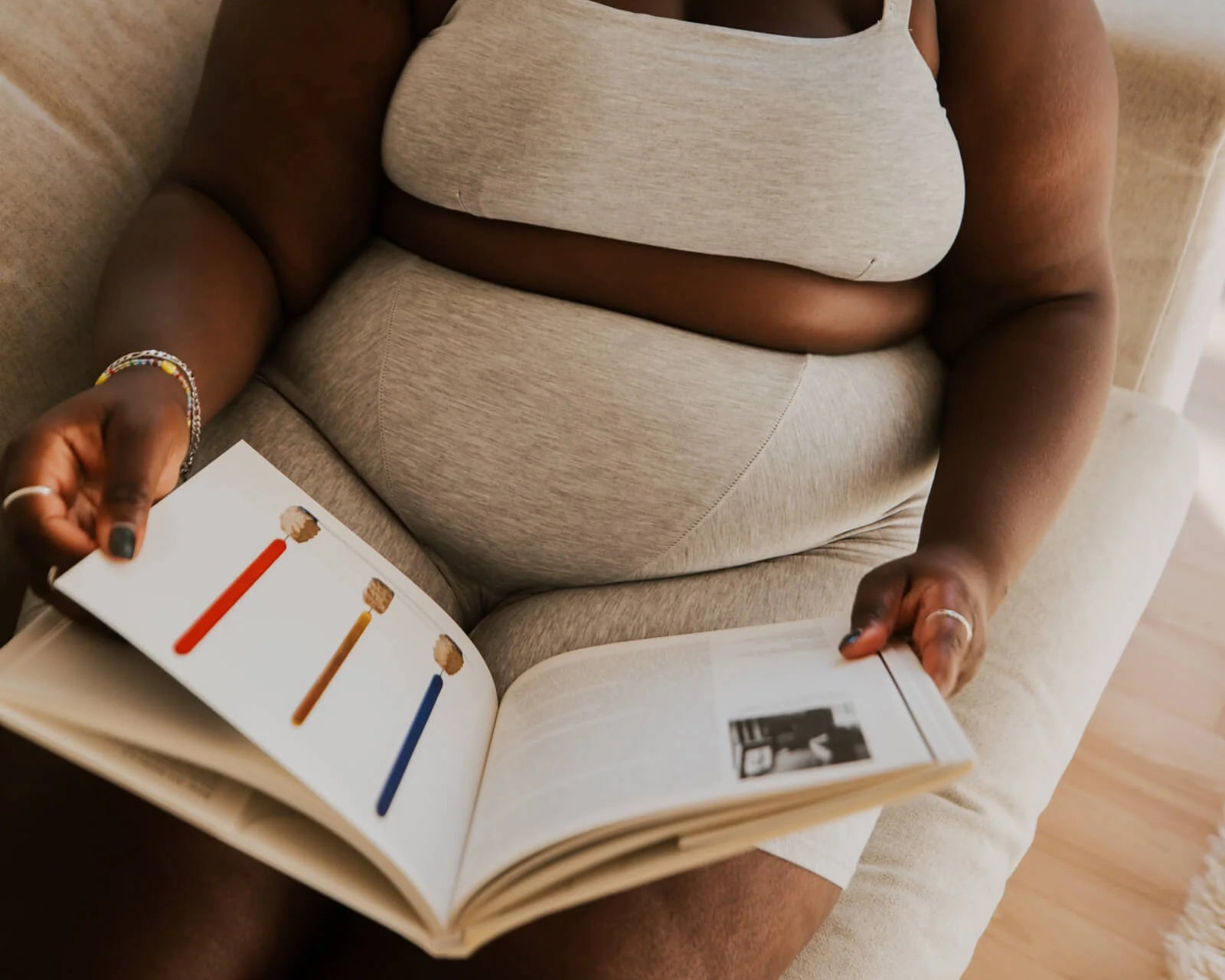 Woman reading a book while wearing the Huha Tata Bralette and underwear in Grey