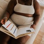 Woman reading a book while wearing the Huha Tata Bralette and underwear in Grey