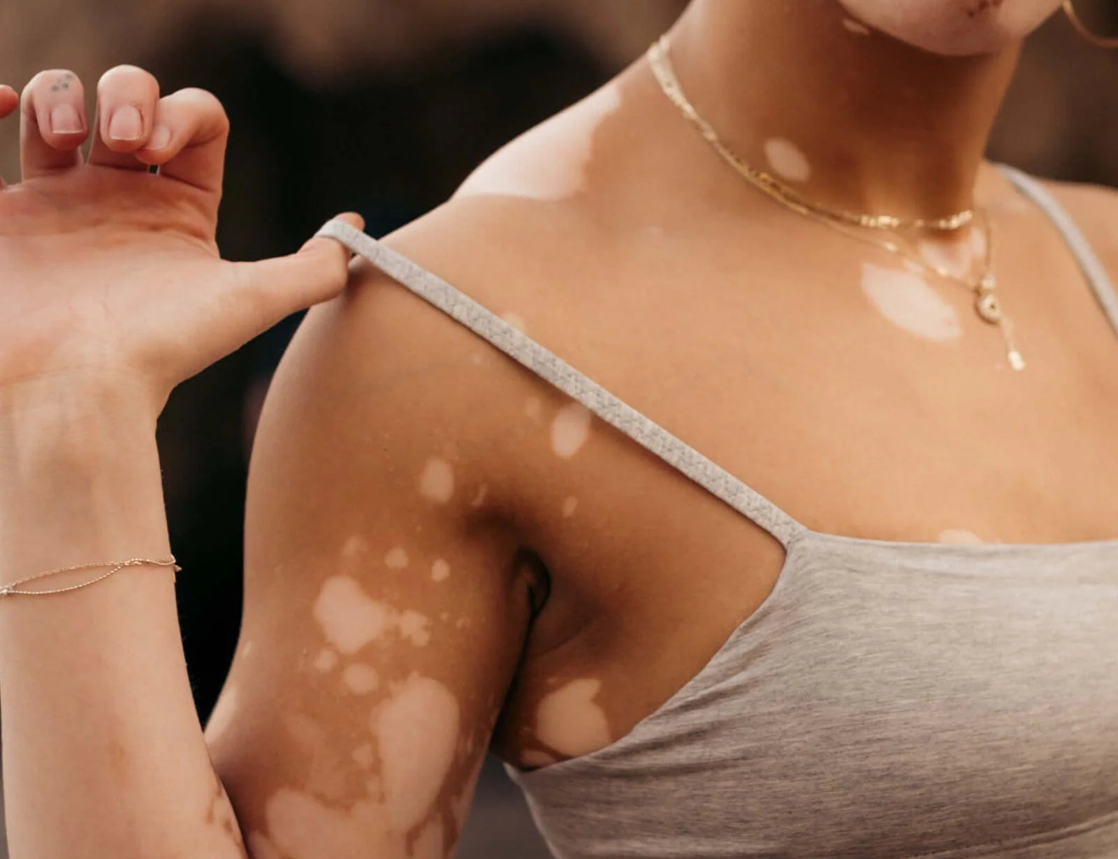 Close-up of a woman adjusting the strap of the Huha Tata Bralette in Grey
