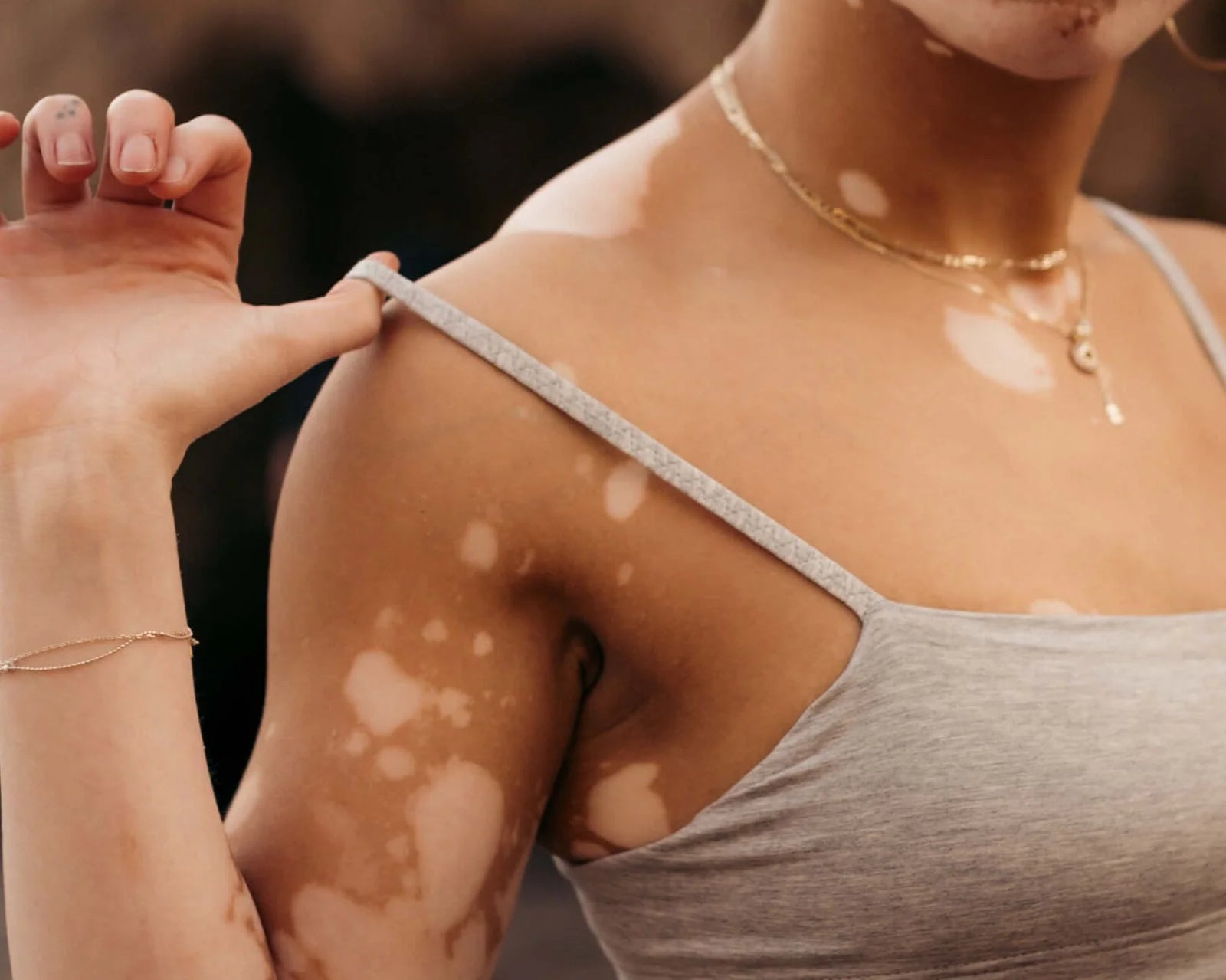 Close-up of a woman adjusting the strap of the Huha Tata Bralette in Grey