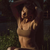 Woman in warm evening light outdoors wearing the Huha Tata Bralette in Tan