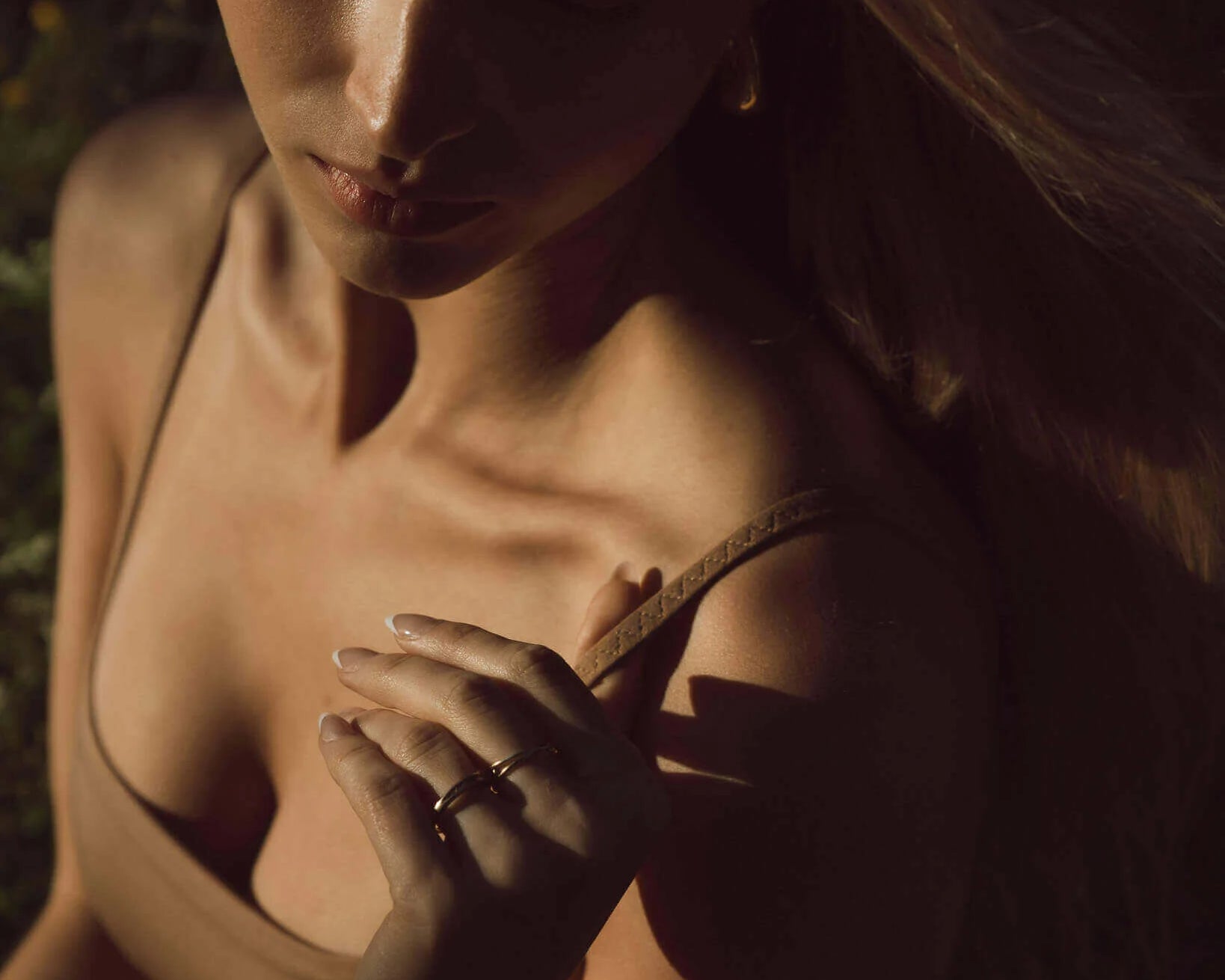 Close-up of a woman in shadowed light wearing the Huha Tata Bralette in Tan