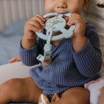 Baby in a navy sweater chewing the Jujube Roarsome Silicone Teether Ring
