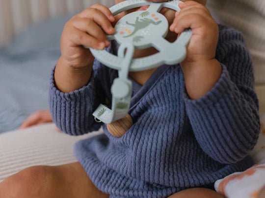 Baby in a navy sweater chewing the Jujube Roarsome Silicone Teether Ring