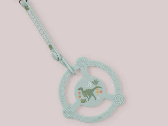 Jujube Roarsome Silicone Teether Ring, a sage green dinosaur-print teether with a pacifier clip