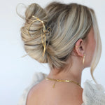 Kaxi Bow Pin in gold holding a loose blonde updo, back view
